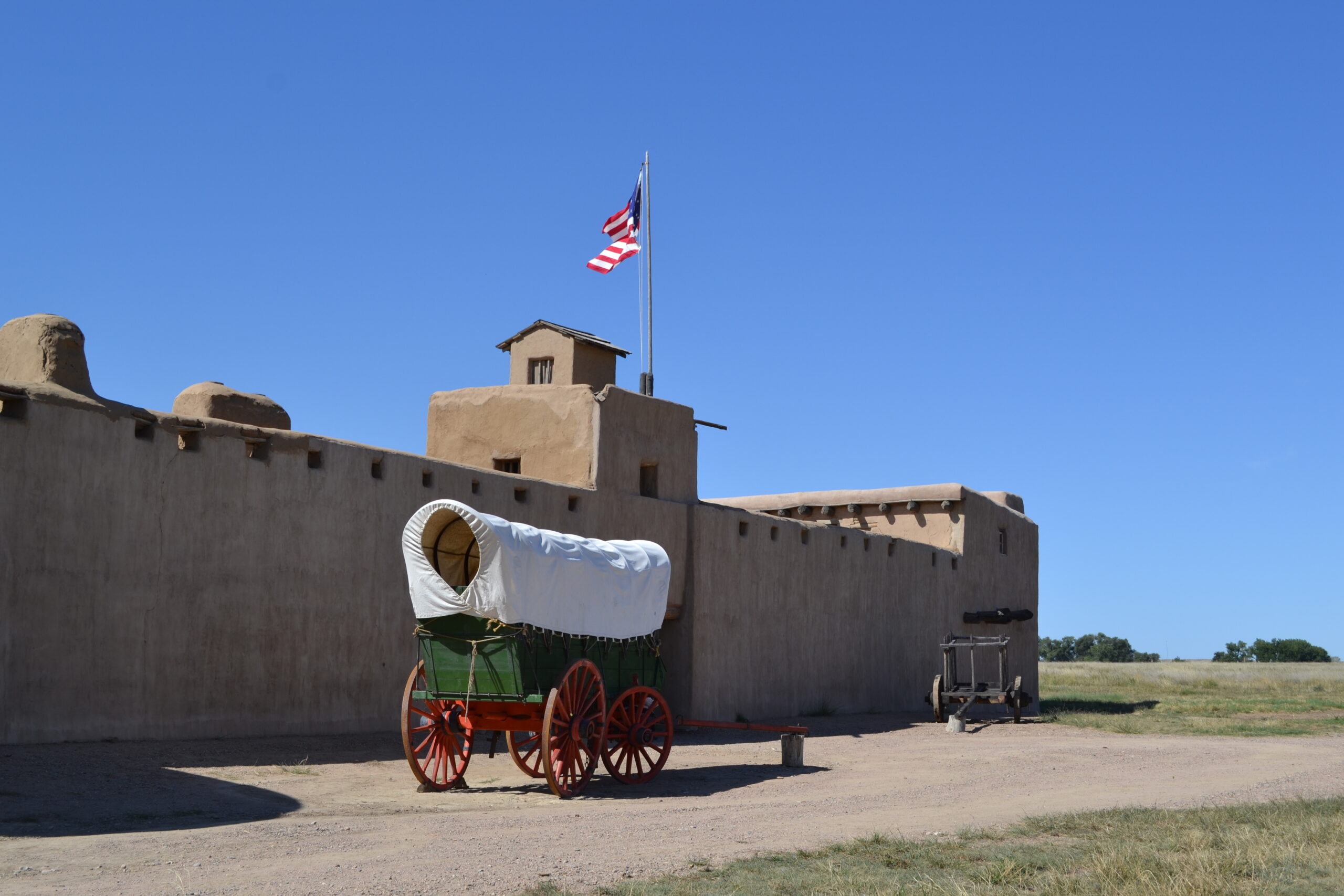 a wagon sits in front of the adobe structure known as bents old fort