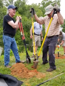 Two men dig post holes for an interpretive sign