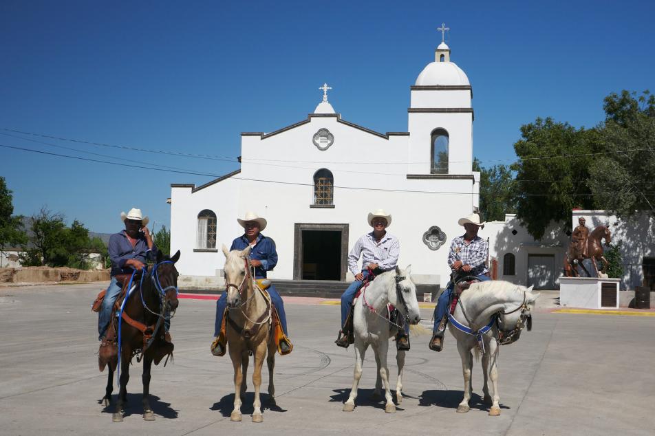 Four men on horseback in front of a church