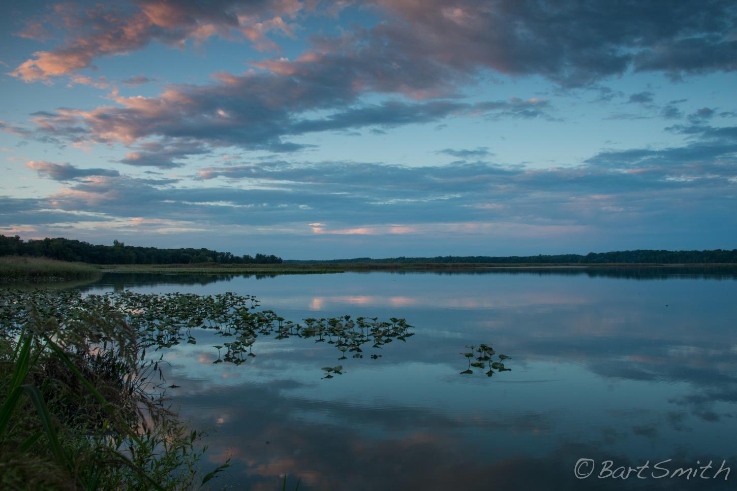 Lake reflecting cloudy sky at dusk