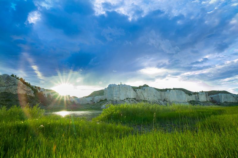 Grassy meadow during sunny day with mountains in the background