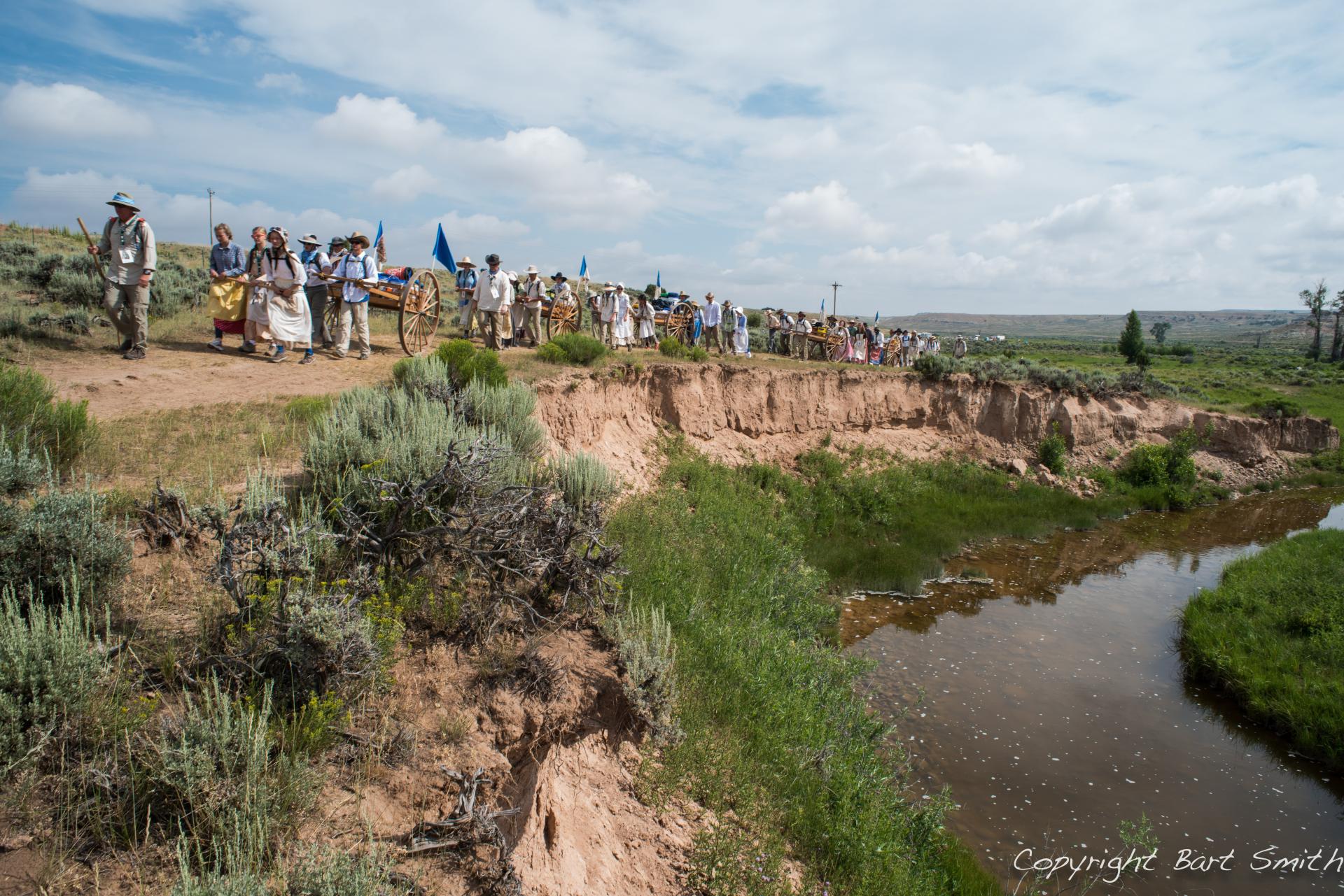 Group of individuals walking along a trail by a river