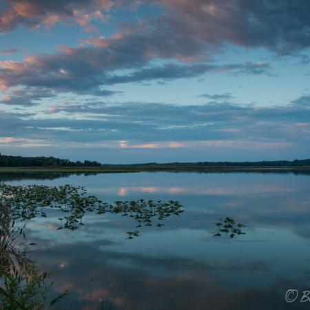 Lake reflecting cloudy sky at dusk