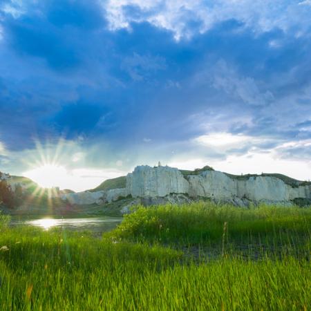 Grassy meadow during sunny day with mountains in the background