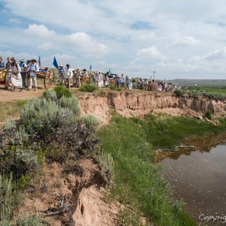 Group of individuals walking along a trail by a river